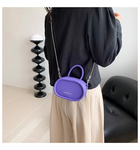 Detail of purple mini crossbody bag with litchi texture and silver chain strap