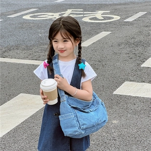 Girl wearing a dark blue denim crossbody bag with adjustable strap in street setting