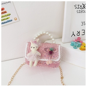 Detailed close-up of pink sequin girl's purse with pearl handle and plush bunny charm