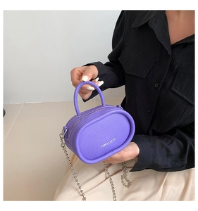 Purple litchi grain mini handbag held by model showing chain strap and size detail