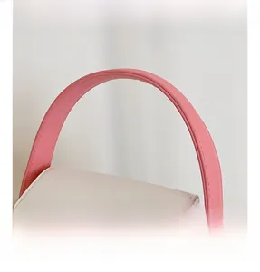 Détail de la poignée en cuir rose et du rabat crème avec fermoirs dorés du mini sac