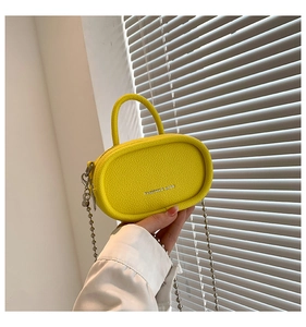 Detail of a bright yellow mini crossbody bag featuring pebble leather and silver bead chain