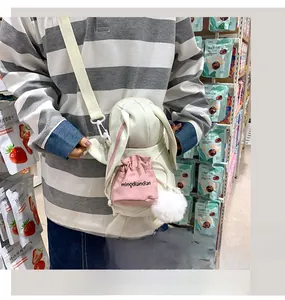 Dettaglio della borsa a tracolla bianca a forma di coniglio con tasca rosa e pompon