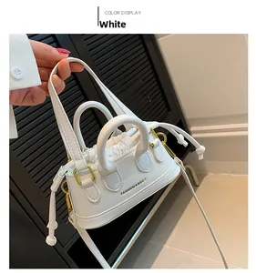Detailed shot of white mini crossbody bag with gold lettering and drawstring pouch