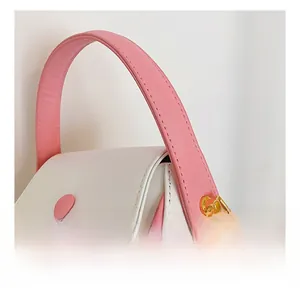 Détail de poignée rose et crochets dorés sur sac à bandoulière blanc pour filles