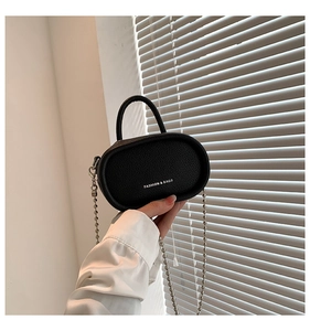 Detail of black pebbled leather mini bag with silver chain strap and top handle