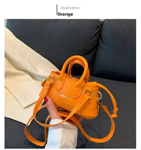 Detailed shot of an orange mini handbag with gold hardware and adjustable strap