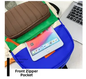 Front zipper pocket of color-block canvas backpack showing tablet storage capacity