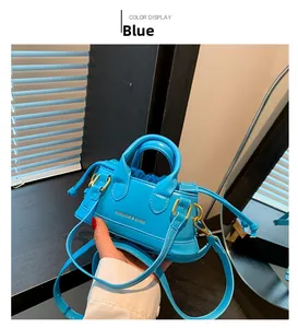 Detailed shot of a mini blue crossbody bag with fashion text and gold metal hardware