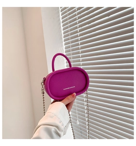 Detail of magenta lychee leather mini bag with silver chain and white logo text