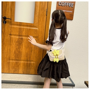 Detail of kids straw crossbody bag with yellow sunflower and white lace edge in outdoor setting