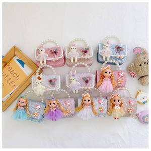 Flat lay of colorful children's sequin handbags with pearl handles and doll charms