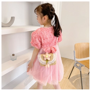 Detail of pink floral dress with large bow and cute woven flower crossbody bag for girls