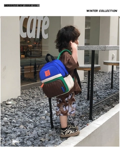 Kid's color-block canvas backpack featuring navy and beige panels in an outdoor cafe setting
