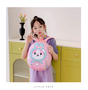 Pink cartoon rabbit hardshell backpack worn by a young child in a cozy home setting