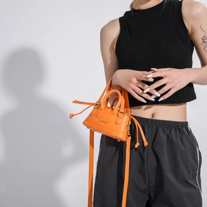 Orange mini crossbody bag with drawstring side details and fashion typography text