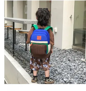 Outdoor shot showing a child wearing a colorful color-block canvas backpack with padded straps