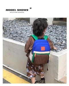 Outdoor shot of kid wearing color-block canvas backpack with green straps on rocky path