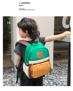 Detailed side view of boy wearing a color-block waterproof canvas backpack outdoors