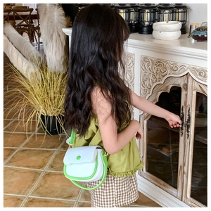 Fillette portant un petit sac bandoulière en cuir blanc avec des détails de bordure verts