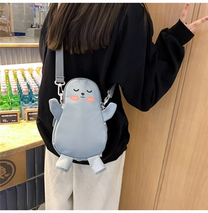 Dettaglio della borsa a tracolla in peluche azzurro con tracolla grigia indossata da modella
