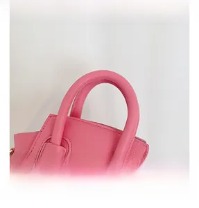 Detail shot of pink lychee grain leather mini handbag with comfortable padded handle