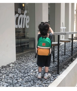 Detail of color-block toddler backpack showing green, yellow and brown panels on a child