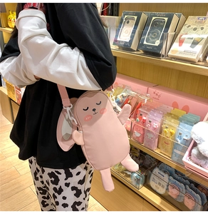 Dettaglio della borsa a tracolla con coniglio di peluche rosa indossata da modella