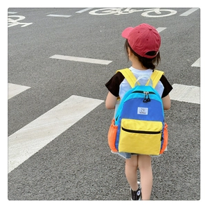 Détail d'un sac à dos enfant tricolore avec badge lapin porté sur le dos de l'enfant