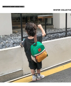 Outdoor lifestyle shot of a colorful color-block kids canvas backpack with brown straps