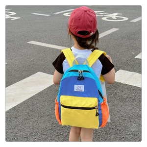 Vue extérieure d'un enfant portant un sac à dos coloré en patchwork bleu et jaune