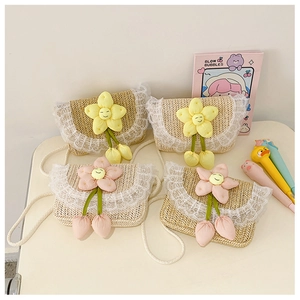 Detail view of woven children's straw bags featuring lace trim and plush flower charms
