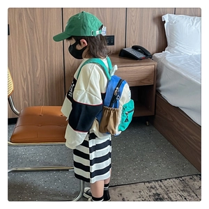 Vue latérale d'un enfant portant un mini sac à dos multicolore avec poche latérale élastique