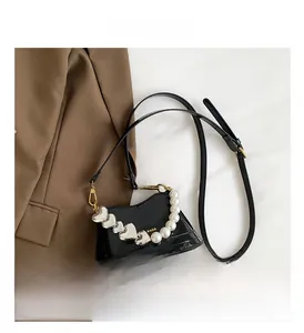 Dettaglio mini borsa in pelle verniciata nera con perle e borchie a cuore argentate