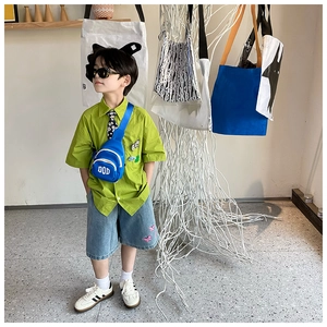 Detail of a kids' blue PU crossbody bag with DOD lettering part of a stylish outfit