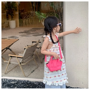 Mini magenta crossbody bag for girls shown on a child model in an outdoor setting