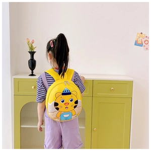 Close-up of a yellow toddler backpack with 3D tiger pattern worn by a young child