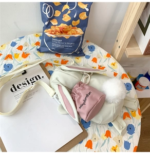 Dettaglio di una borsa a tracolla a forma di coniglio bianco con coda di peluche