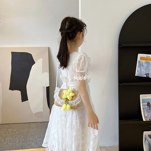 Girl wearing summer woven crossbody bag with lace edges and a yellow smiley flower charm