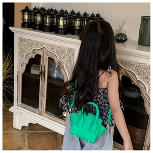 Detail of bright green mini basket handbag with textured leather and metal strap hooks