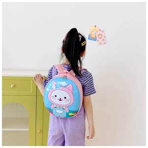 Rear view of a child wearing the cute pink and blue egg-shaped cat backpack in a room