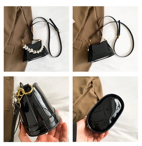 Dettaglio mini borsa in vernice nera con manico di perle e ciondolo a cuore argento
