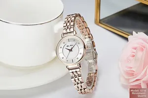 Detailed close-up of rose gold mesh strap watch with crystal markers on white dial