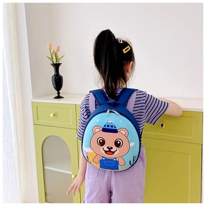 Blue hardshell kids backpack with bear print shown on a child's back in a room