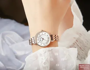 Detail of rose gold metal chain strap and white quartz watch face with diamond markers
