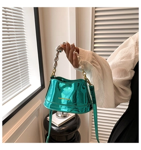 Detail of teal metallic bucket bag featuring pearl beaded handle and silver spheres