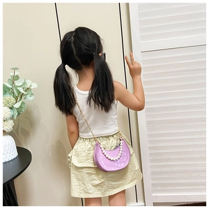 Detail of purple croc-effect kid's bag with pearl handle and chain strap on model