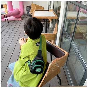 Kid back view wearing black and neon green DOD chest bag with contrast strap details