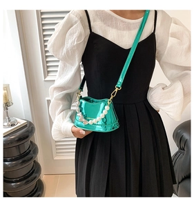 Close-up of vibrant green metallic mini bag with pearl chain heart charm and strap