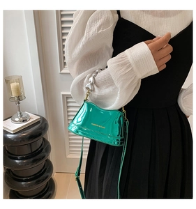Detail of green patent leather bag featuring silver heart-shaped chain and fashion text